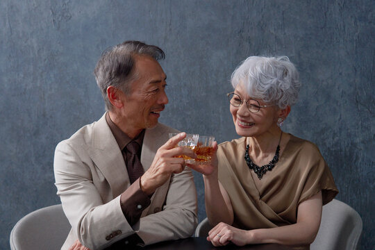 ウィスキーを飲むシニアの夫婦　乾杯　黒背景