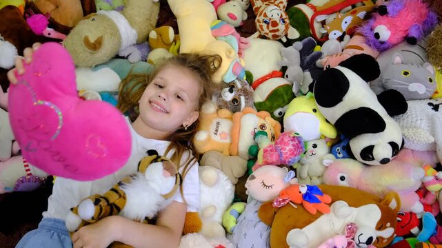 Towering pile of toys. A cheerful girl is surrounded by a huge, colourful pile of stuffed toys, her eyes sparkling with delight.  Pure, unfiltered joy of a child&rsquo;s special day.