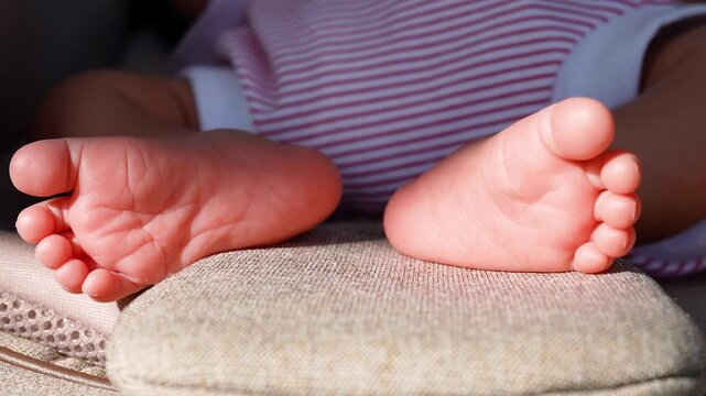 Close-up of Cute Newborn Baby Feet Resting in a Stroller in Warm Sunlight
