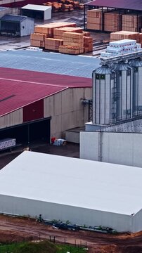 Industrial sawmill facility with timber storage and processing silos in Latvia, aerial vertical