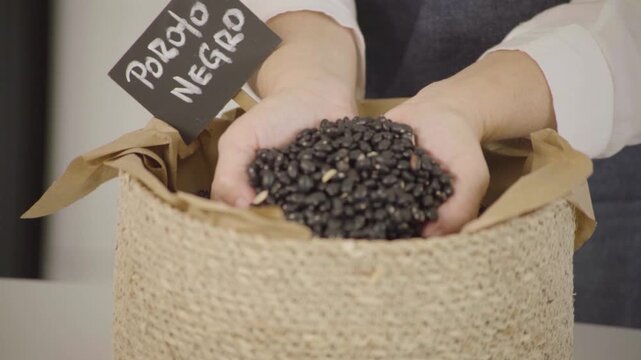 Poroto negro seco, legumbre para alimentaci&oacute;n saludable y prote&iacute;na vegetal, mano sosteniendo y dejando caer granos en c&aacute;mara lenta (Slow Motion), Footage cocina, comida