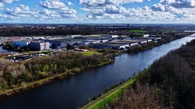 A large industrial complex adjacent to a river, with a backdrop of expansive skies filled with clouds. Suitable for urban development or industrial studies.