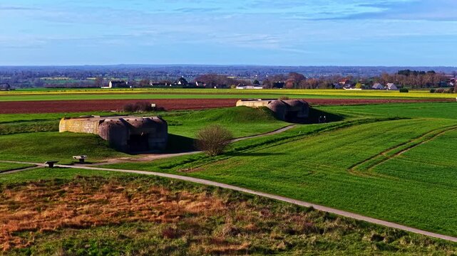 Two historic bunkers sit amidst expansive green fields in Longues-sur-Mer. A perfect fit for history documentaries or educational content.