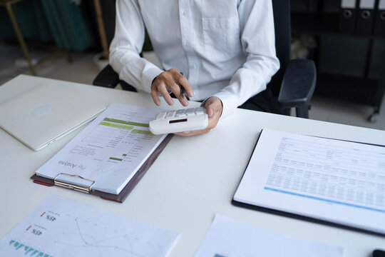 Businessman holding and press botton on calculator over documents