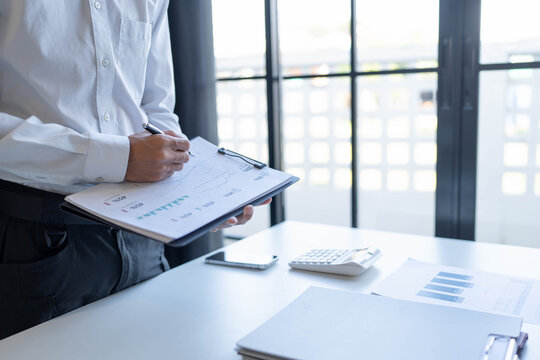 Businessman standing chekking documents with pen