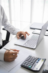 Fototapeta premium Asian businessman writing on document and typing on laptop