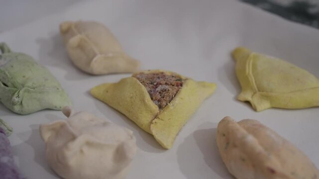 Traditional Argentine frozen empanadas featuring regional fold styles including repulgue crimps and open faced pastry shapes with assorted savory fillings, slow motion arc reveal kitchen shot.