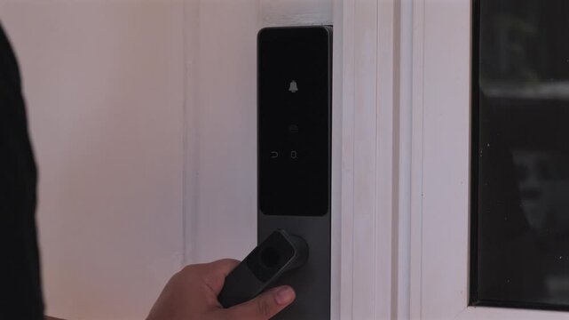 A close up video of a person tapping an RFID key fob onto a modern black smart lock to open a door.