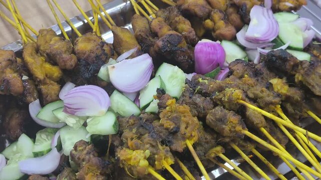 Freshly grilled chicken and beef satay sticks served neatly inside a takeout box. The delicious skewered meat is arranged perfectly on a table, ready to eat.