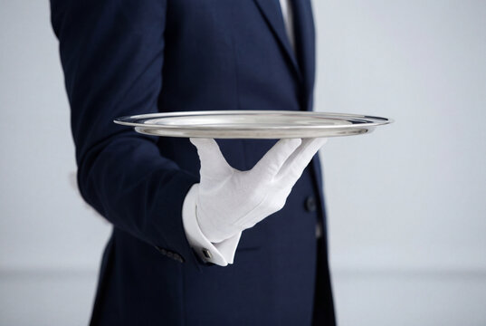 Waiter wearing white gloves holding an empty silver serving tray