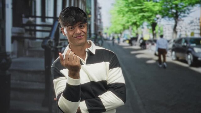 Man with fist to chest and crossed arms on street wearing black and white striped shirt; playful confidence.