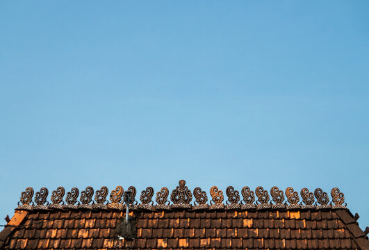 Traditional Javanese roof tile featuring an artistic curved detail at its top, known as a makuta or crown motif. Made of clay, this tile is a signature element of traditional Indonesian architecture.