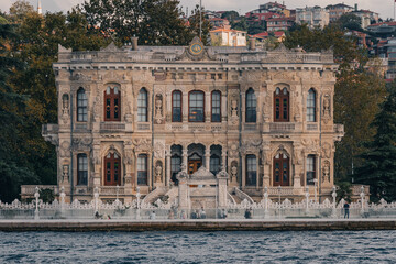 Fototapeta premium Fachada detallada del Palacio de Küçüksu en Estambul, Turquía. Arquitectura neobarroca otomana junto al estrecho del Bósforo con turistas paseando. Ideal para turismo y cultura.