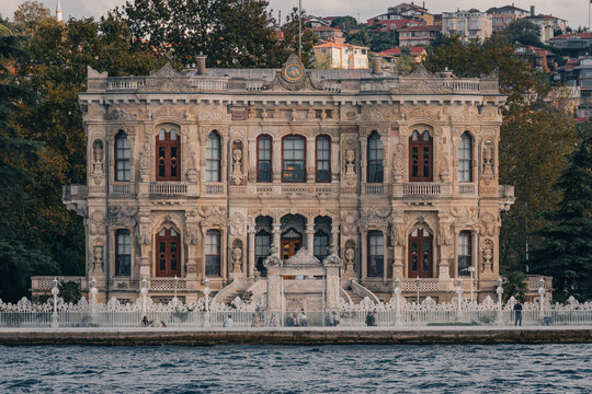 Fachada detallada del Palacio de K&uuml;&ccedil;&uuml;ksu en Estambul, Turqu&iacute;a. Arquitectura neobarroca otomana junto al estrecho del B&oacute;sforo con turistas paseando. Ideal para turismo y cultura.