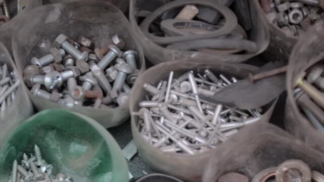 Nuts, nails, bolts, and screws in plastic jars. They are grouped and separated in the bottom part of cut plastic bottles.