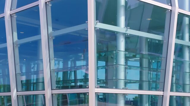 Modern glass building facade with blue reflective windows, metal frames and structural columns, showing contemporary corporate architecture in daylight