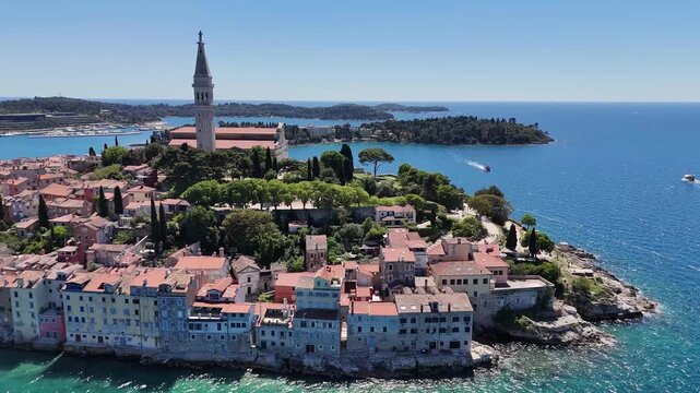 Aerial view of Rovinj waterfront homes, historic church bell tower, and vivid Adriatic Sea along the Istrian coast.
