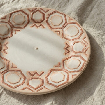 Handmade ceramic plate with subtle geometric relief pattern inspired by Brazilian azulejos on natural linen cloth