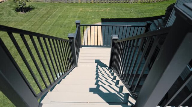 Modern elevated backyard deck attached to house featuring black metal railings and outdoor stairs in residential neighborhood