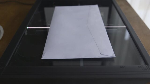 A white envelope is placed on the glass surface of a flatbed scanner, ready for scanning. Ideal for office technology or document digitization themes.