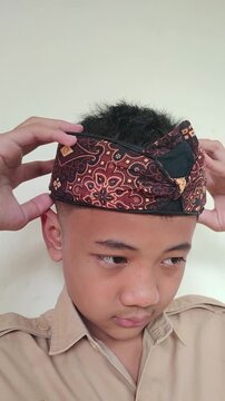 Front view of Southeast Asian teenage boy wearing a traditional sundanese batik head covering or iket kepala sunda