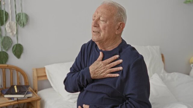 Man clutching chest on bed in building with hand over heart, possible heartattack and visible discomfort; distress urgency.