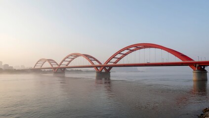 Fototapeta premium Red arched bridge over calm water at sunrise with misty fog in serene landscape