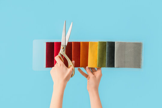 Hands holding fabric swatch book with scissors, textile selection and design process, interior decorating and upholstery material choices