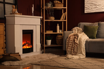 Obraz premium Cozy living room interior with electric fireplace, comfortable sofa, and decorative shelving for home comfort