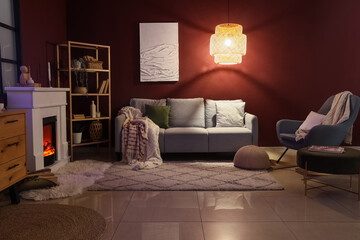 Obraz premium Cozy living room interior with fireplace, sofa, armchair, and warm lighting for home comfort and relaxation