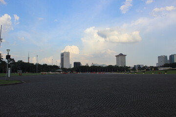 Fototapeta premium Wide urban square paved with stone bricks under cloudy blue sky during daytime.