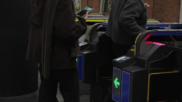 Passengers passing through automatic IC card ticket gates with green arrows at Japanese train station in Japan