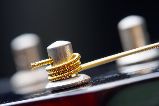 Closeup view of winded new string onto a guitar tuner