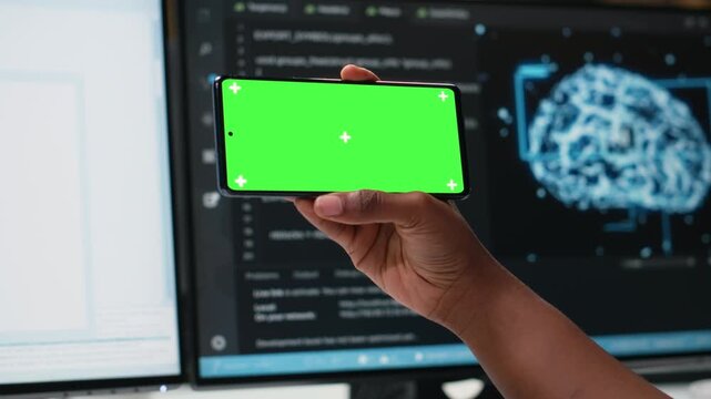 Isolated screen smartphone used by admin in office working to fix bugs in artificial intelligence system. Employee in tech startup using chroma key mockup mobile phone to watch videos.