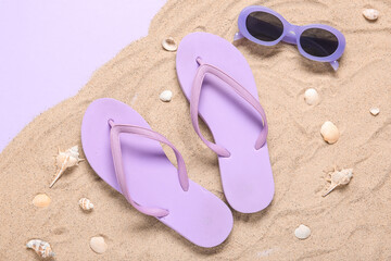 Obraz premium Summer vacation beach essentials: purple flip flops and sunglasses on sand with seashells, top view, this flat lay composition captures the relaxed atmosphere of a holiday getaway