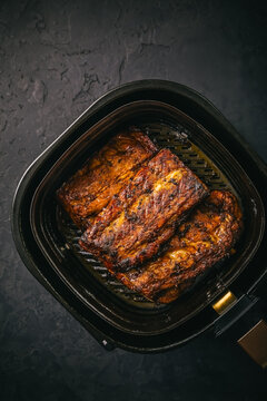 Modern cooking - preparing juicy spare ribs with honey sauce in airfryier, BBQ meat