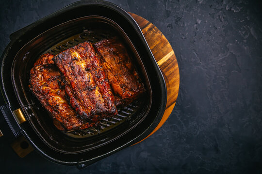 Modern cooking - preparing juicy spare ribs with honey sauce in airfryier, BBQ meat