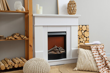 Obraz premium Cozy living room interior with white electric fireplace, wooden shelf, and decorative elements for home comfort