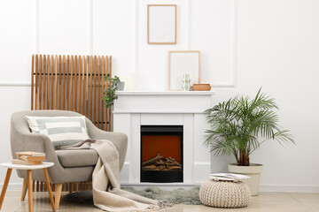 Obraz premium Cozy living room interior with comfortable armchair, electric fireplace, and houseplants for home comfort