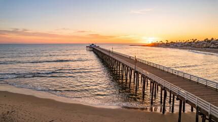 Obraz premium Newport Beach Pier stretching into the Pacific Ocean during a golden sunset in California
