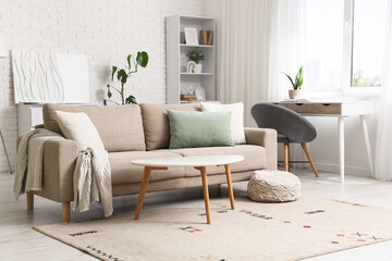 Modern living room interior design with comfortable sofa, coffee table, desk, and white brick wall decor © Pixel-Shot