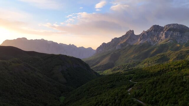 Dramatic sunset scene in Picos De Europa mountains of northern Spain with view of the rocky limestone peaks of the Central and Western massifs (Aerial drone video slowly rising up for higher view)