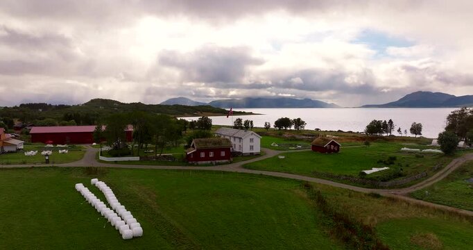 Aerial view of the Kvitnes Gaard farm, restaurant and surrounding green landscape by the fjord in Vesteralen, Northern Norway