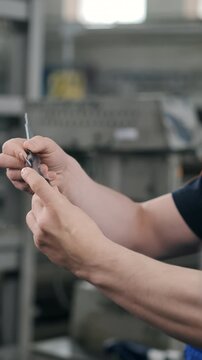 Close up of machinist measuring precision metal component with vernier caliper in manufacturing workshop. Quality control and dimensional inspection in industrial production.