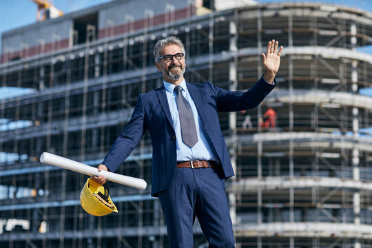 senior businessman architect wearing a protective helmet using a tablet and a blueprint on the construction site
