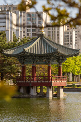 Obraz premium Traditional Korean pavilion on a lake with modern skyscraper apartments in the background