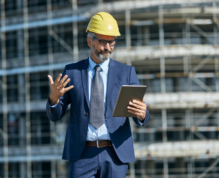 senior businessman architect wearing a protective helmet using a tablet on the construction site