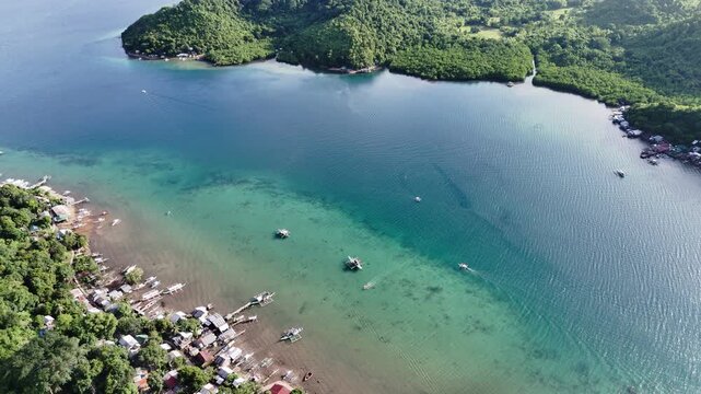 Aerial drone view of Liminangcong Port, revealing stilt houses and coastal housing along a tropical seascape, Philippines
