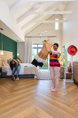 Obraz premium Diverse female friends holding tan or white or black dress on hanger in bedroom, one putting on shoe