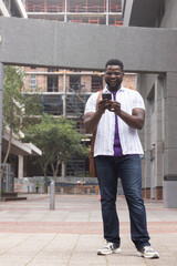 African American man standing in plaza under concrete beam, checking smartphone, scaffold behind © wavebreak3